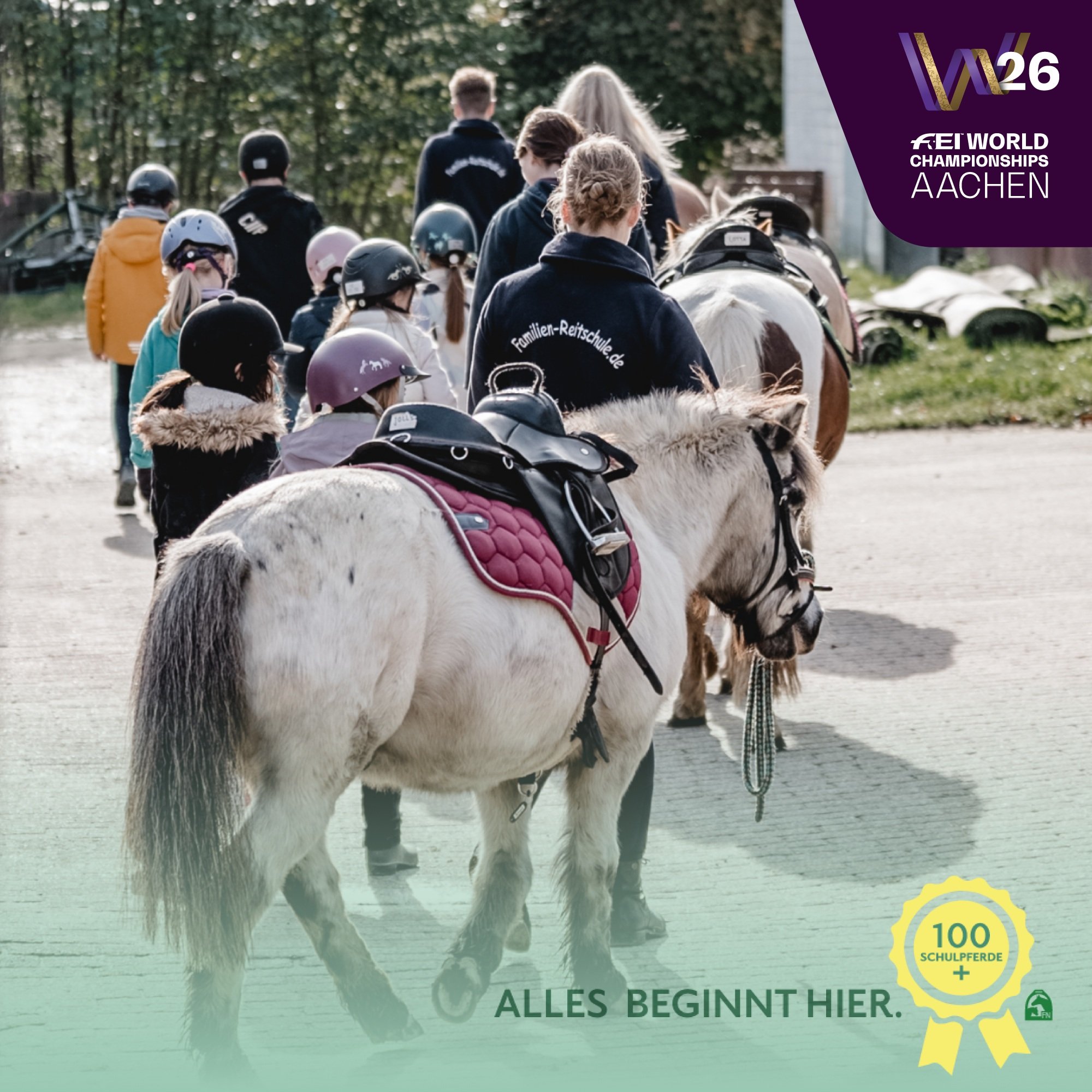 Several children wearing riding helmets walk across a courtyard together with adults and three saddled ponies. At the top right is the logo of the FEI World Championships Aachen 2026. At the bottom right is a yellow seal with the inscription ‘100 school horses+’ and below it the words ‘EVERYTHING STARTS HERE.’